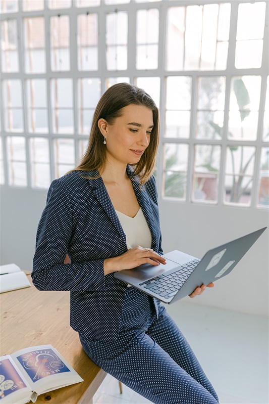 Business portrait for brand designer and strategist, wearing smart casual suit and working on laptop