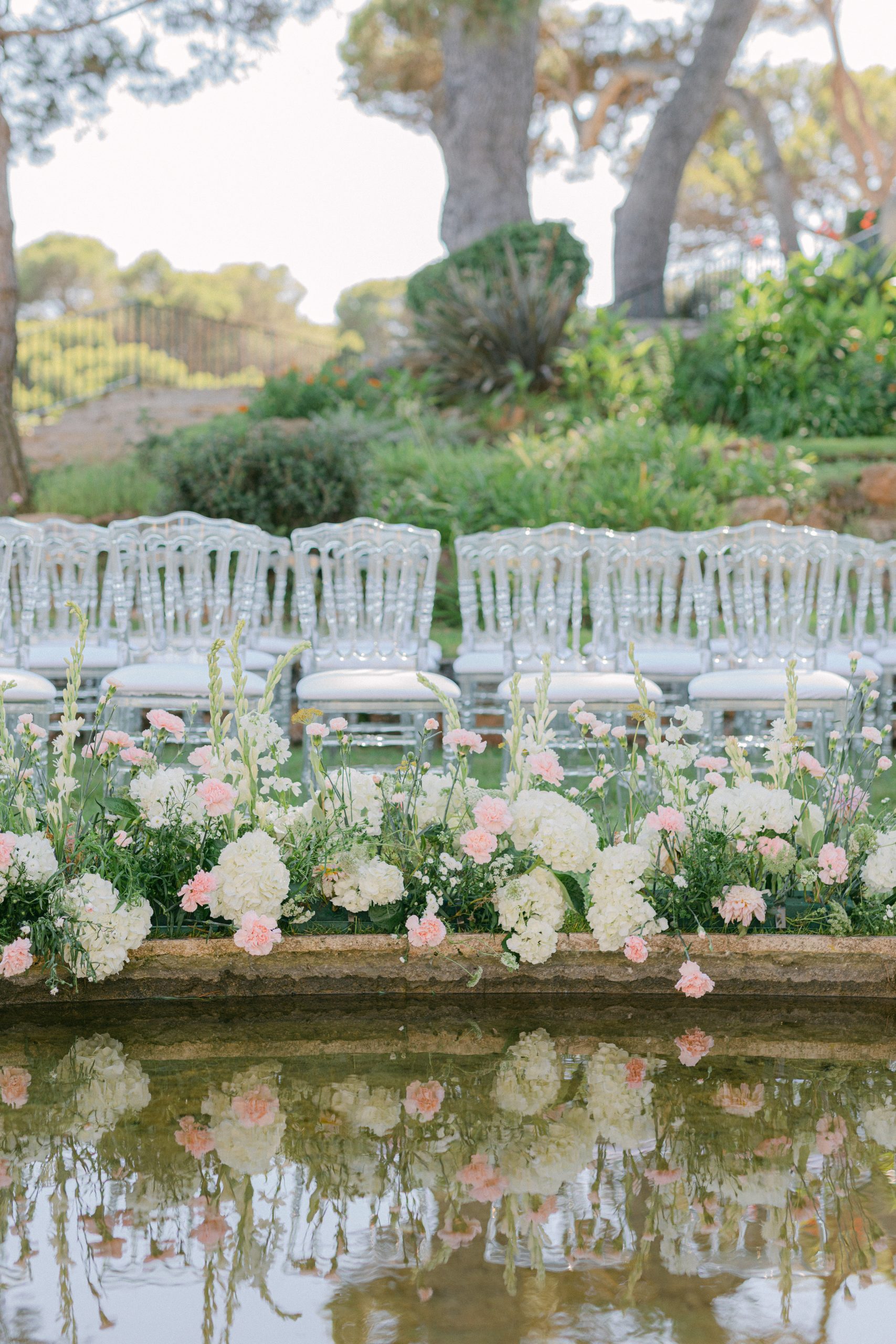 white and pale rose floral decoration with transparent chairs around, chic wedding on mediterranean coast