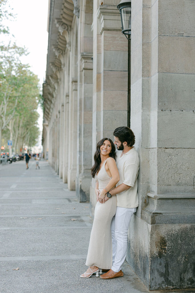 Lovely couple standing next to a beautiful building looking at each other with love after surprise proposal in Barcelona