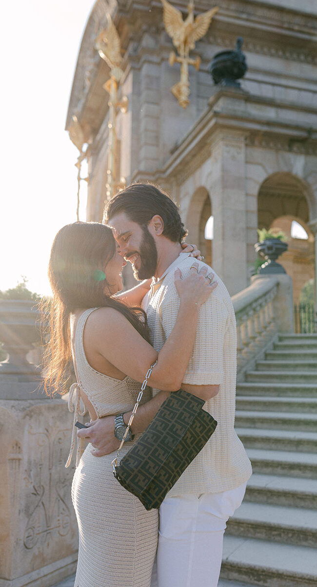 Happy just engaged young couple wearing smart casual and elegant beig outfit with Ciutadella Park on the backdrop