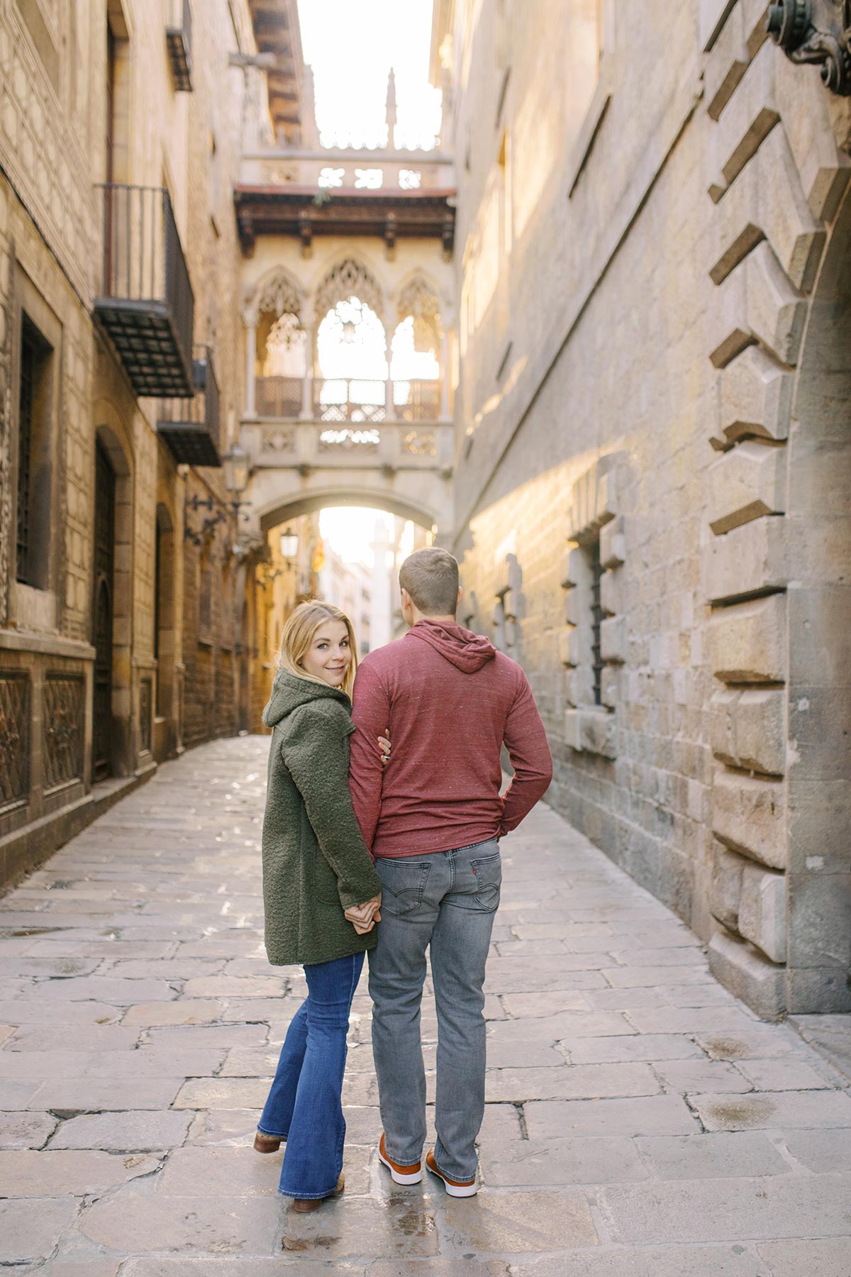 Young couple mesmerising Pont Del Bisbe during the honeymoon photoshoot in Barcelona's Gothic quarter
