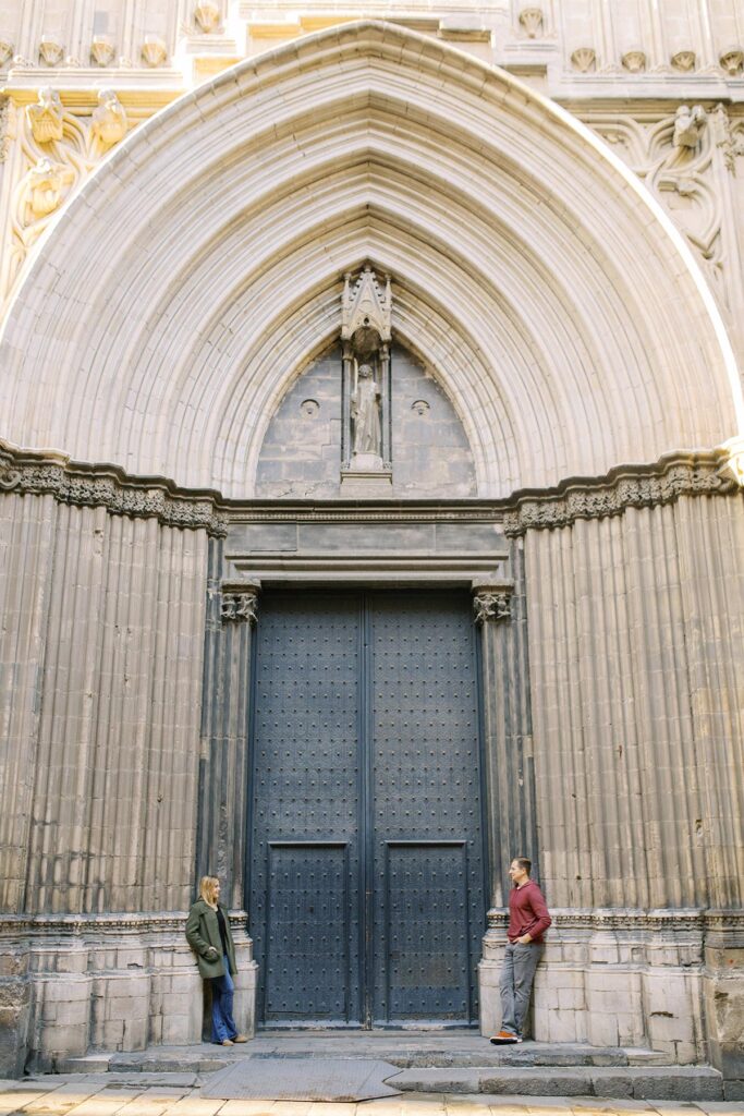 Young couple posing at the huge and authentic door during the honeymoon photoshoot in Barcelona's Gothic quarter