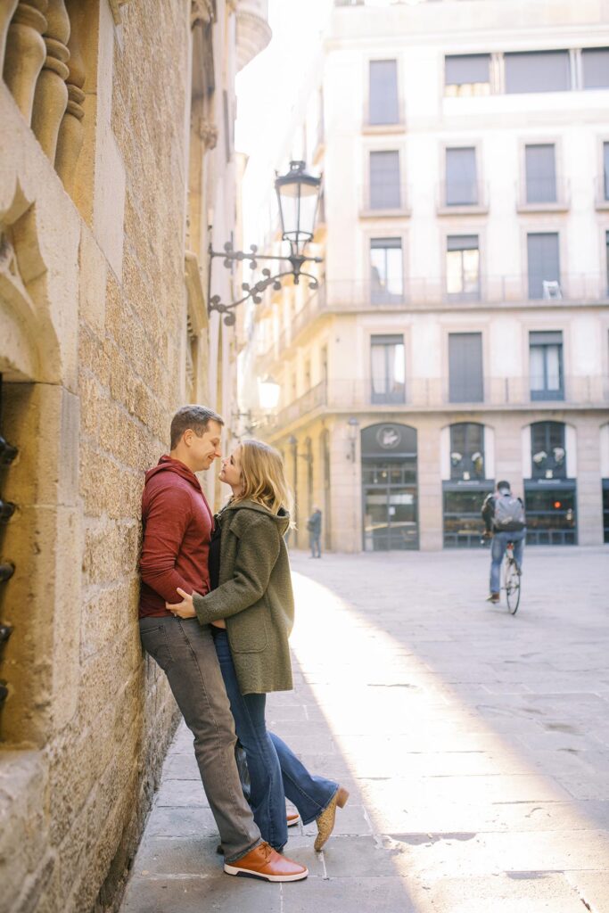 Young couple leaning to the wall and looking to each other with eyes full of love during the honeymoon photoshoot in Barcelona's Gothic quarter