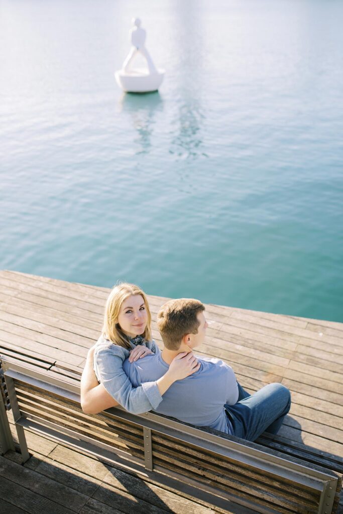 Young couple sitting on the bench near the blue waters at Rambla del Mar during the honeymoon photoshoot in Barcelona