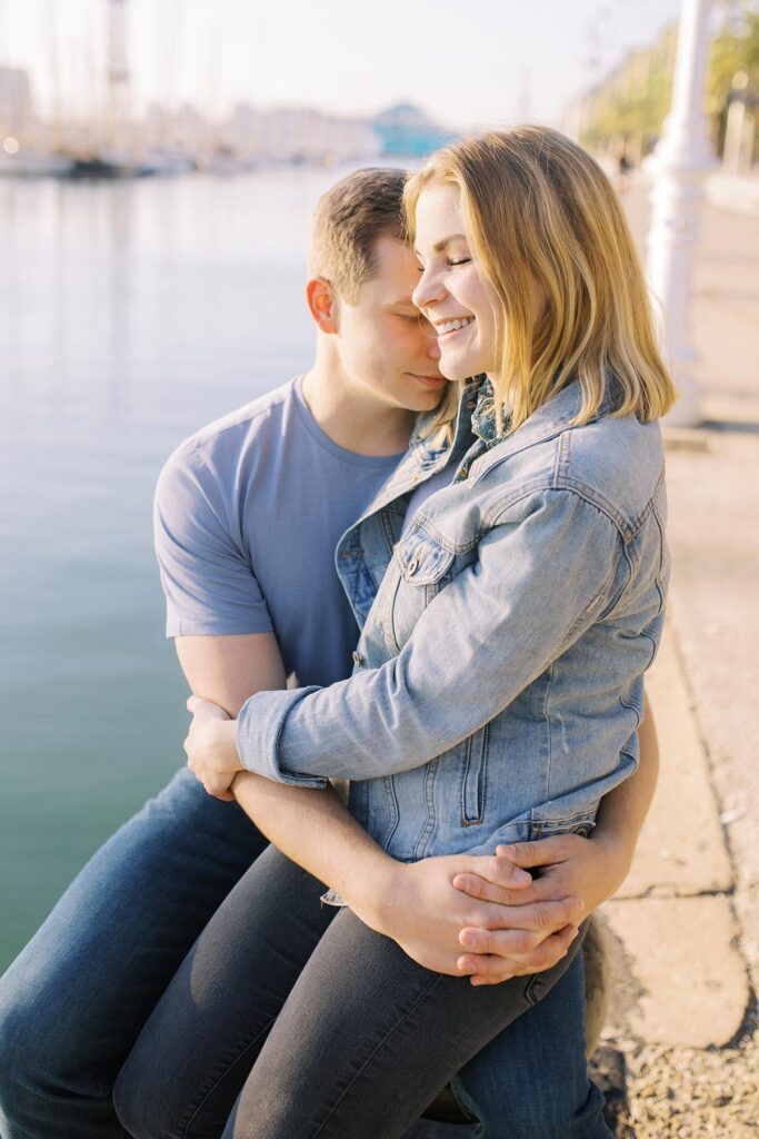 Young couple sitting next to the sea and hugging during the honeymoon photoshoot in Barcelona's Gothic Quarter