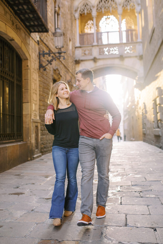 Young happy couple walking down Carrer del Bisbe during the honeymoon photoshoot in Barcelona's Gothic quarter