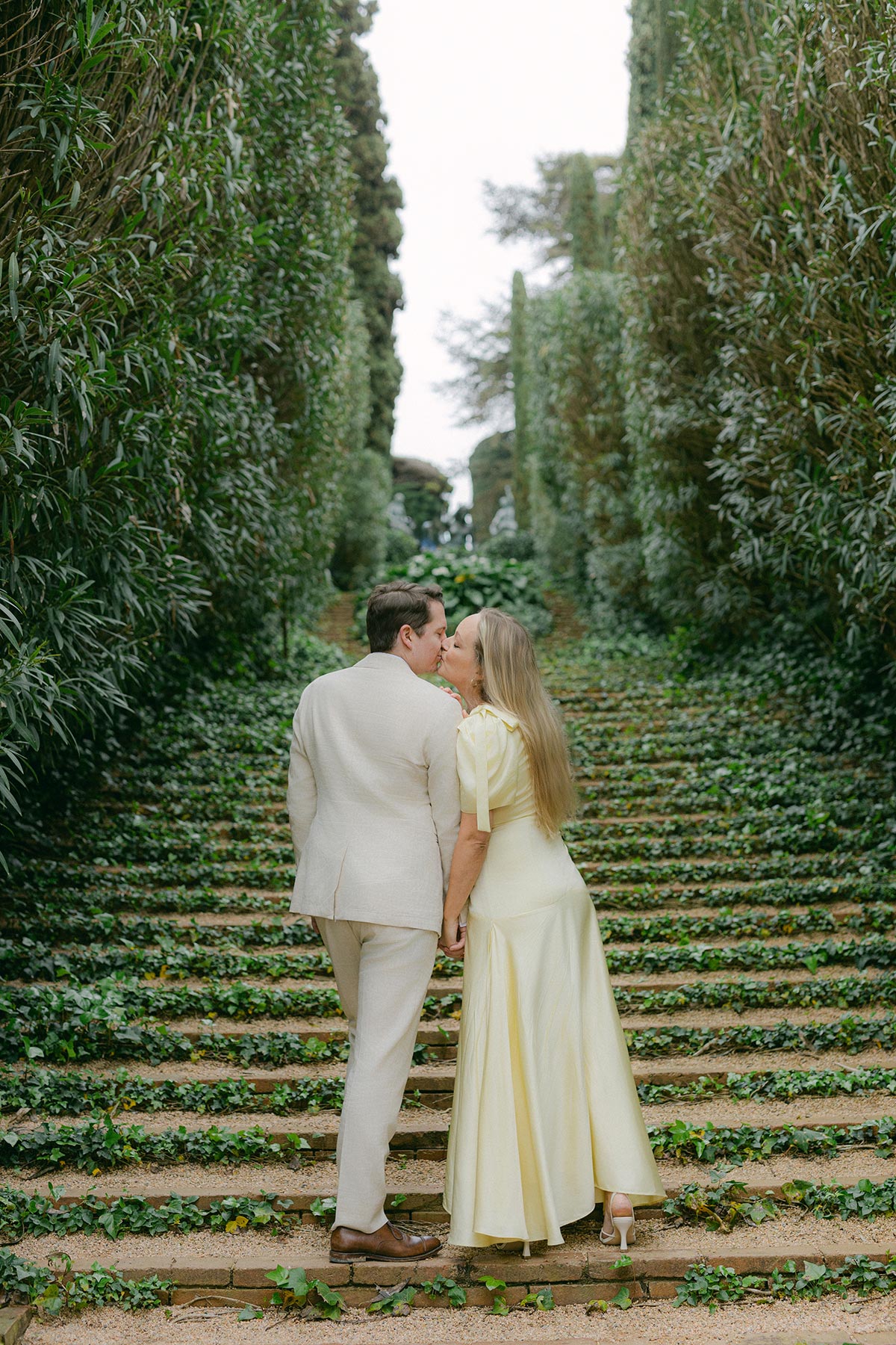 Couple sharing a quiet kiss at garden stairs surrounded at Santa Clotilde Gardens. Captured by an experienced Barcelona engagement photographer