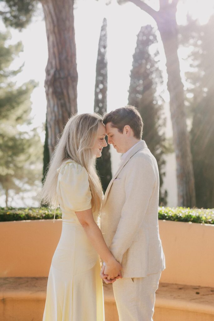 omantic moment of couple hugging under pine trees with ocean views at their Costa Brava engagement shoot.Captured by an experienced Barcelona engagement photographer