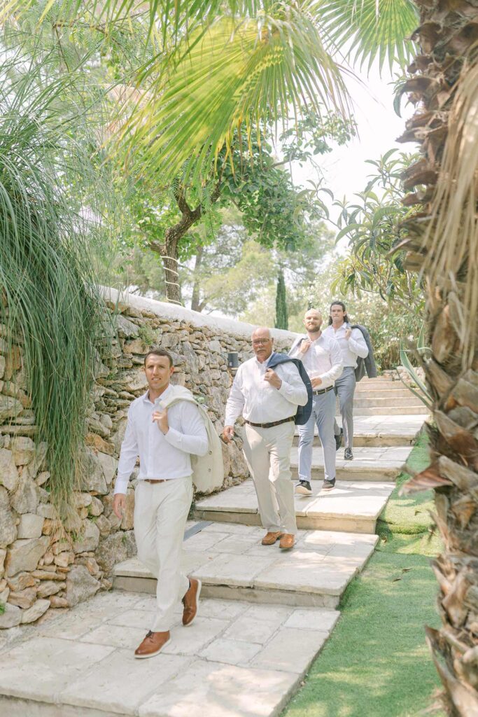 Groomsmen walking through lush gardens at a villa wedding in Sitges, Spain.