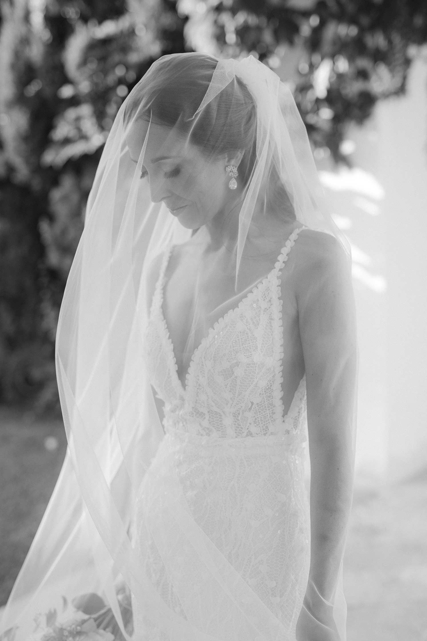 Black and white portrait of the bride looking down through her sheer veil at Hostal La Gavina