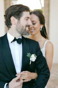 Close-up of the groom smiling as the bride stands behind him during their wedding session at Hostal La Gavina