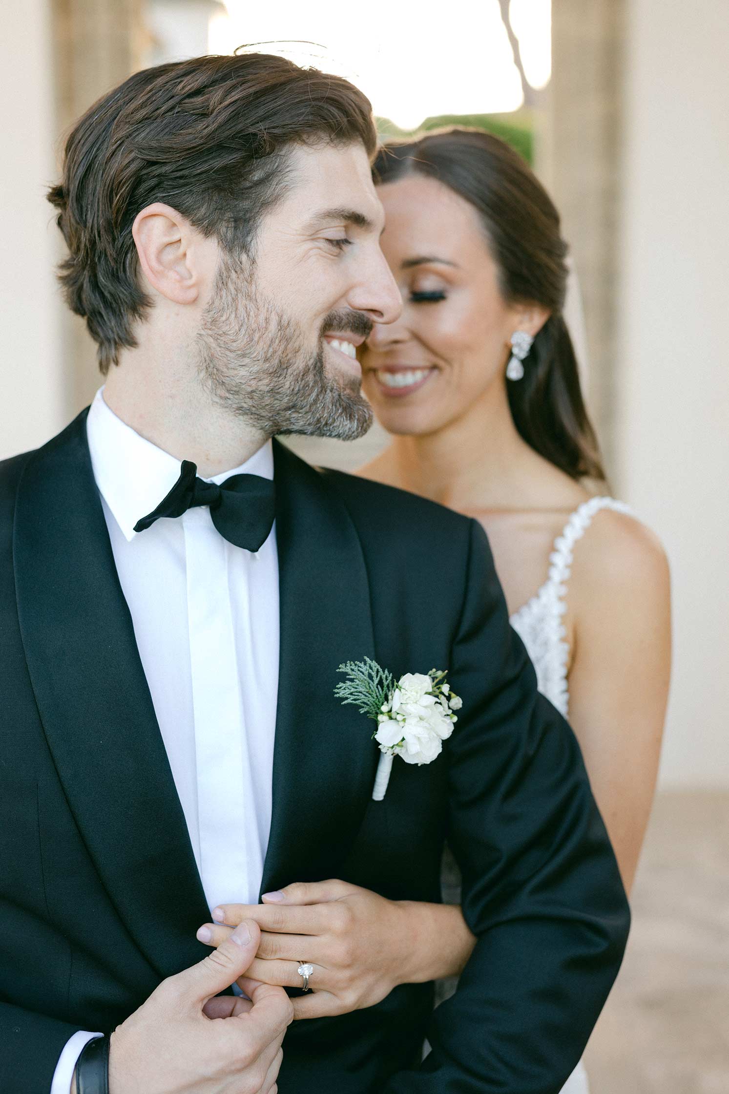 Close-up of the groom smiling as the bride stands behind him during their wedding session at Hostal La Gavina