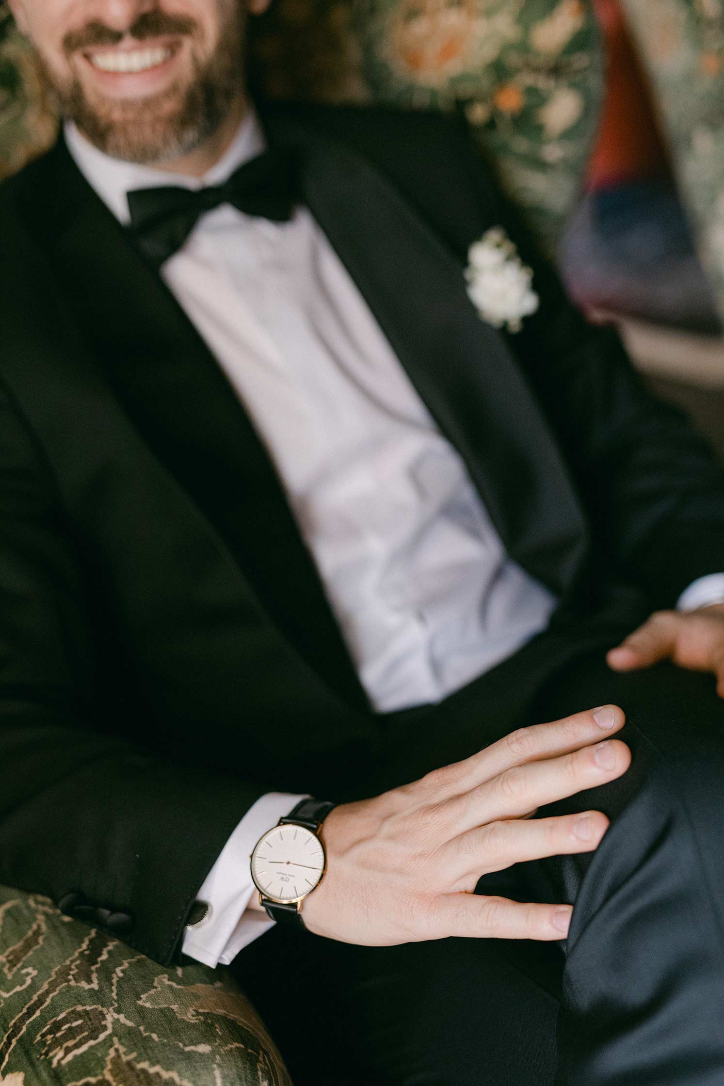 Detail portrait of groom Gonzalo in a black tuxedo showing his watch and boutonniere