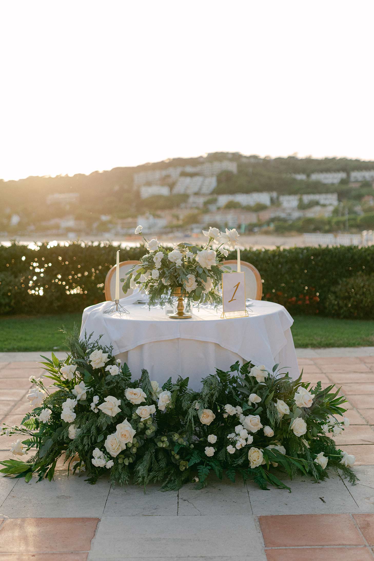 table with white roses and greenery on a stone patio at Hostal La Gavina.
