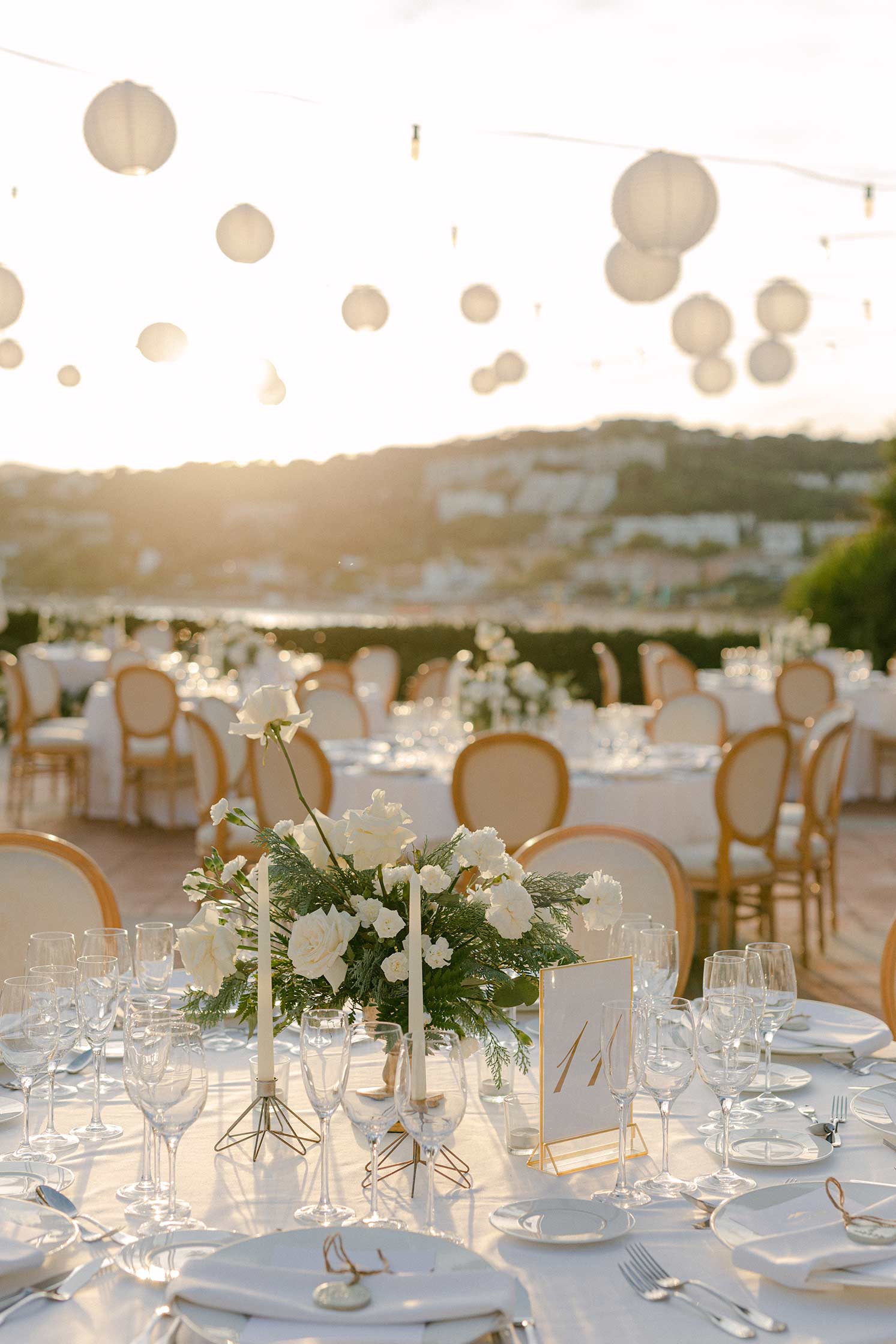 Golden hour wedding reception at Hostal La Gavina featuring white paper lanterns and elegant table settings.