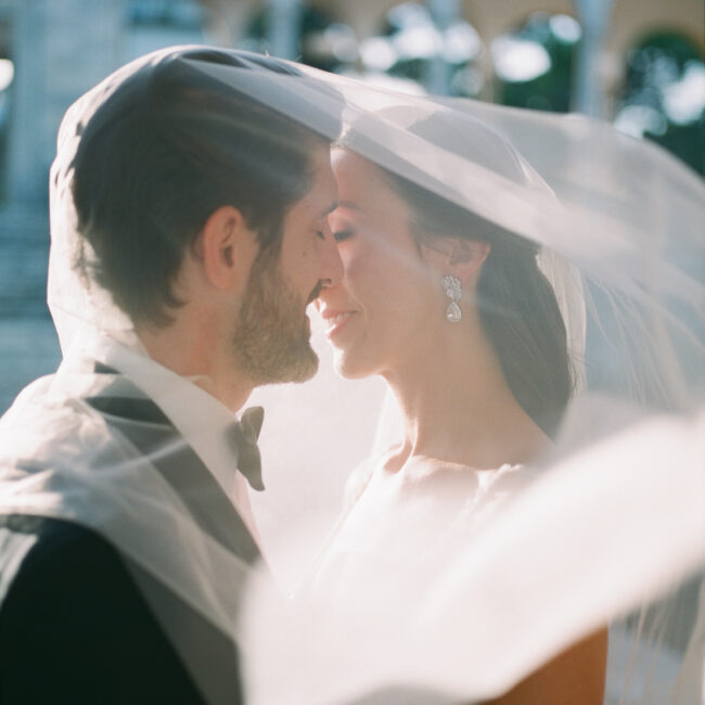 couple kissing below the veil during golden hour at Hostal La Gavina. Barcelona Wedding Photographer Lena Karelova