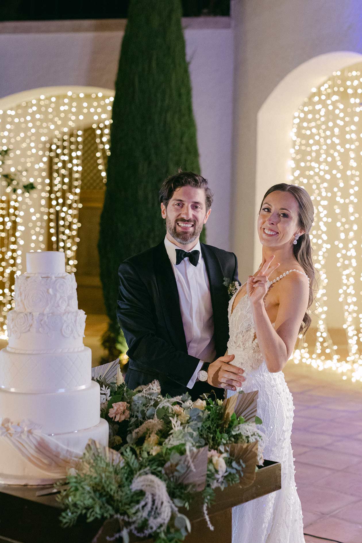 Bride and groom cutting the cake with light on backgrond at Hostal La Gavina; Costa Brava destination wedding photography