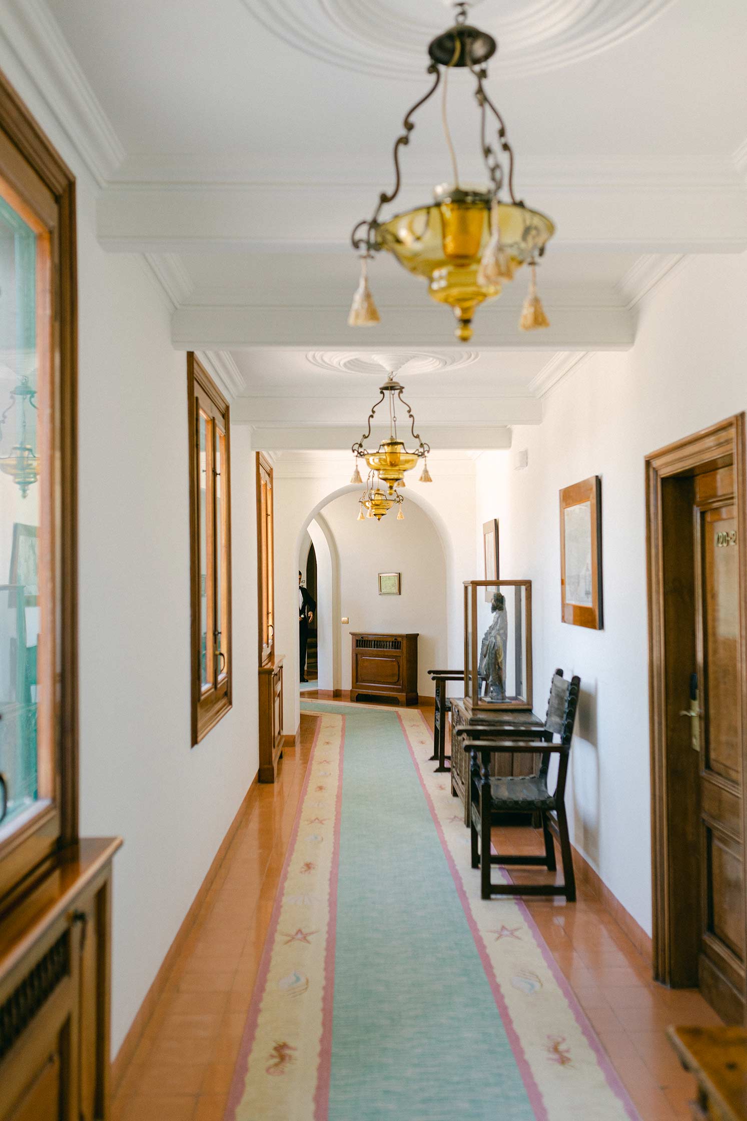 Interior corridor at Hostal La Gavina with vintage lanterns and elegant Mediterranean decor