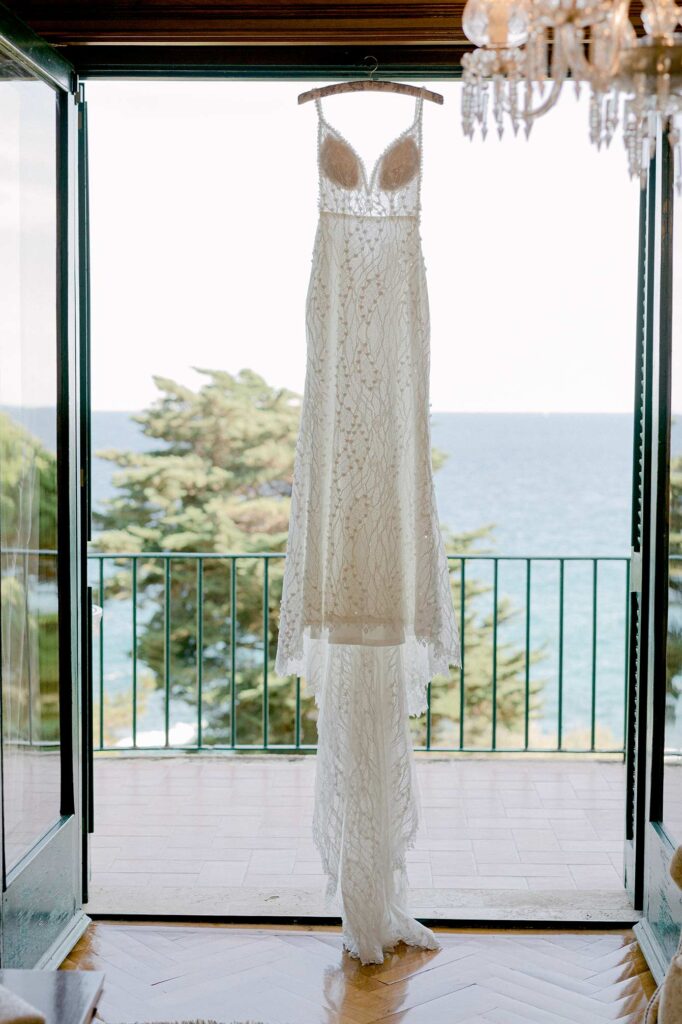 Wedding dress hanging in front of a sea view balcony at Hostal La Gavina in Costa Brava