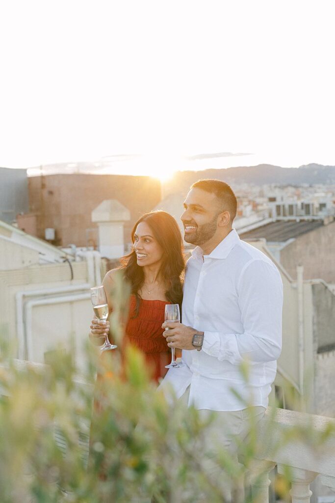 Couple toasting their engagement on a private rooftop terrace with Barcelona skyline views