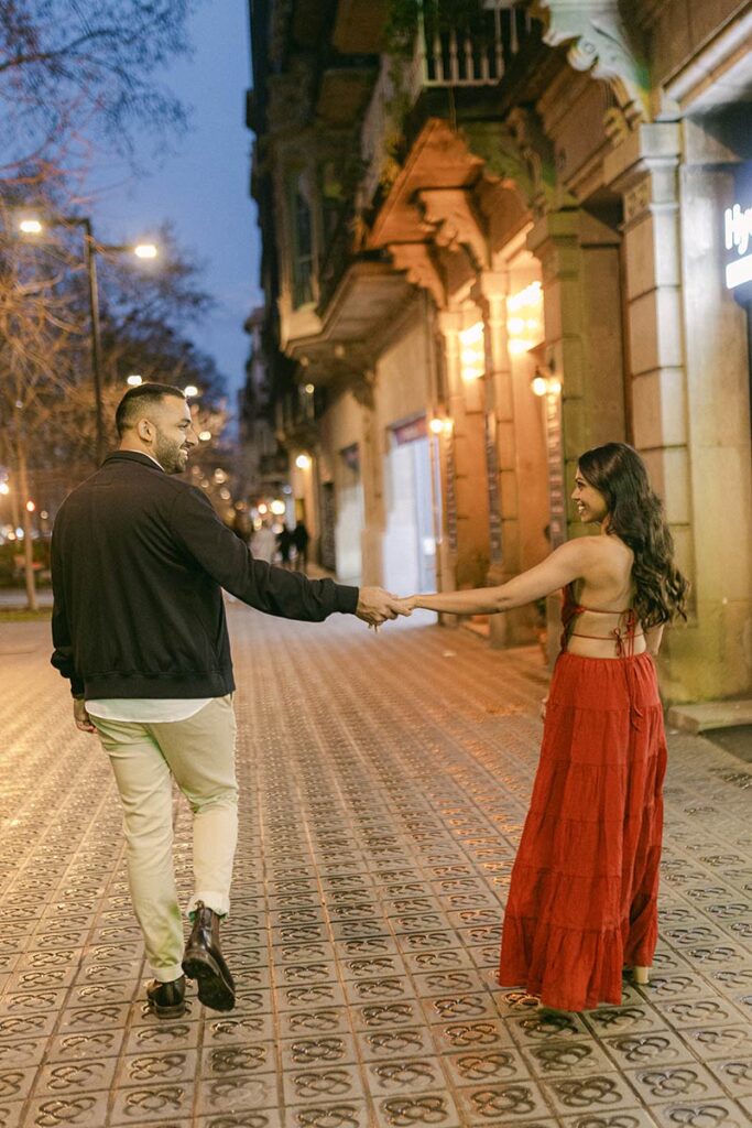 Couple walking through Barcelona at night after their private rooftop proposal