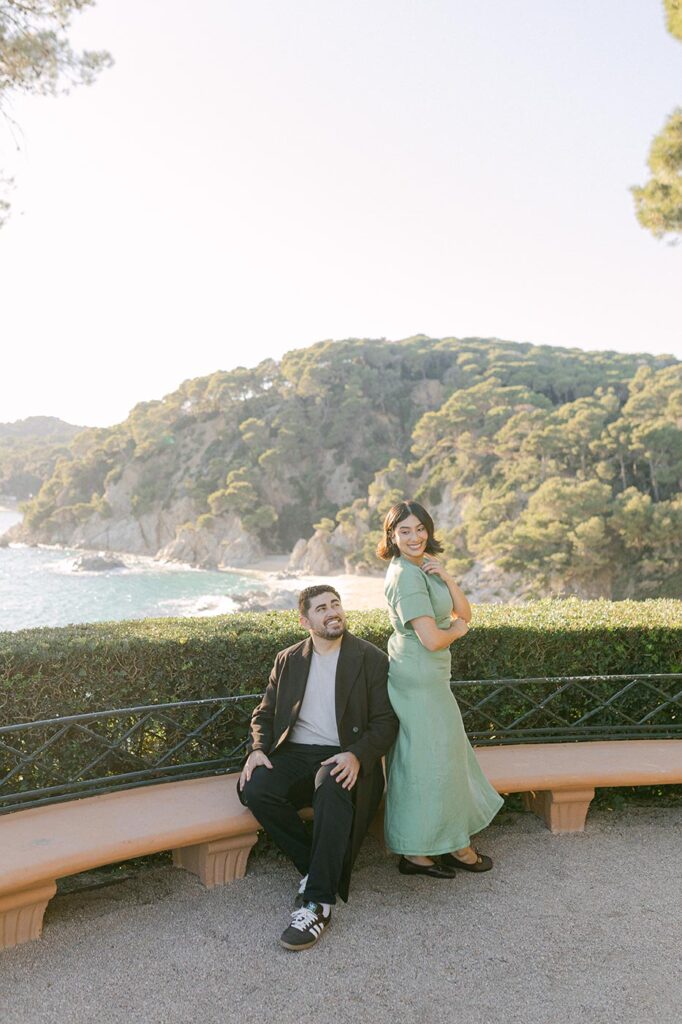 happy couple sitting on the beautiful bench in the garden with sea view. Best locations for surprise proposal on the Costa Brava, Spain