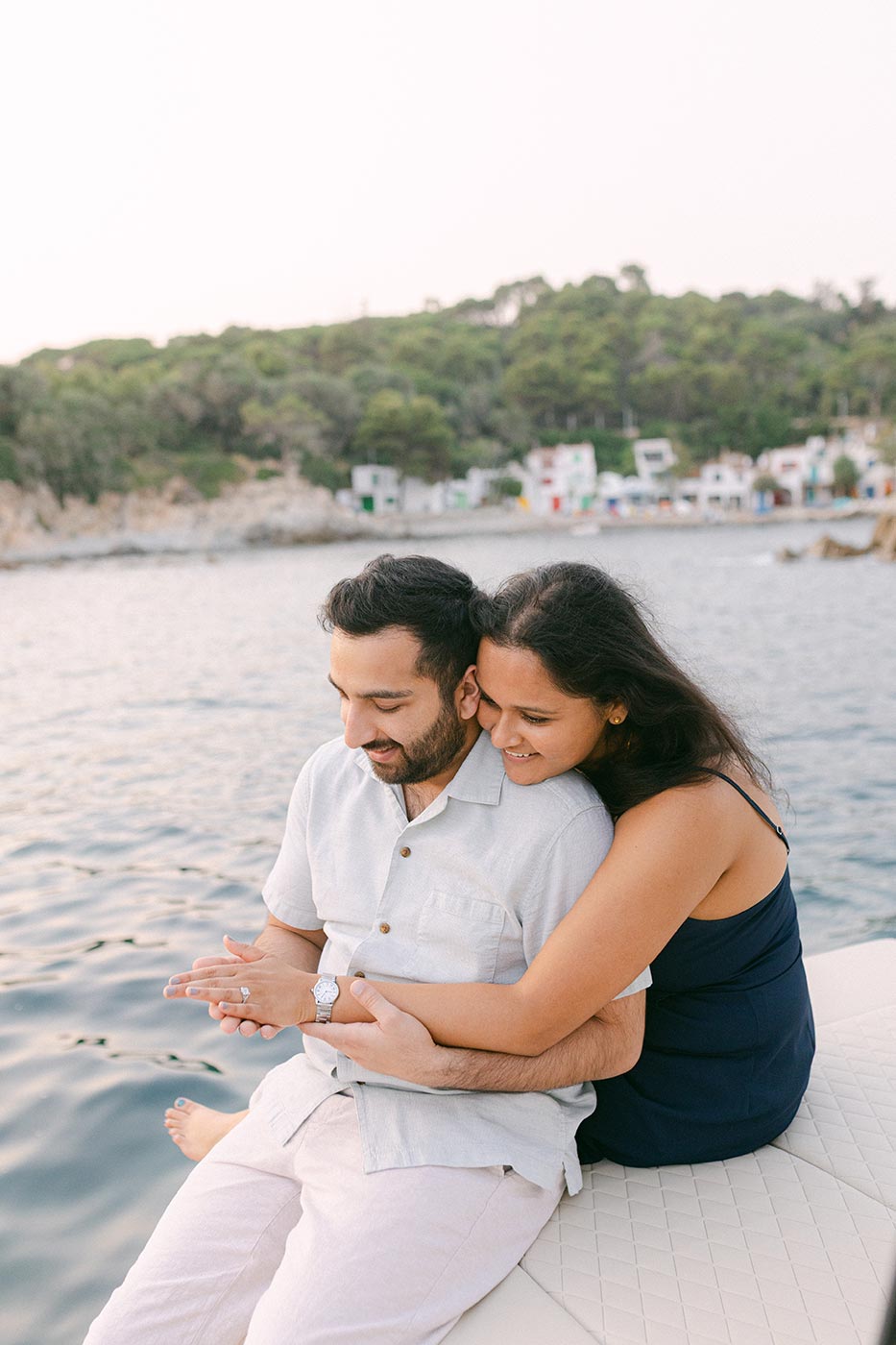 lovely elegant couple sitting in the private boat with costa brava on the background happy after surprise proposal